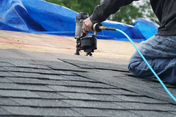 Worker fastening shingles with a roofing nailer