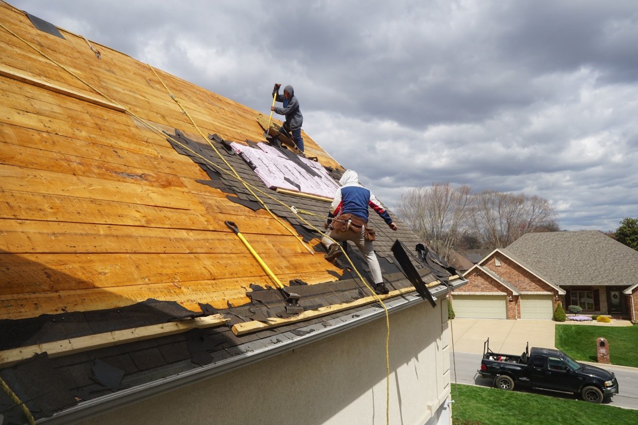 Illustrative workers removing roofing materials from a roof